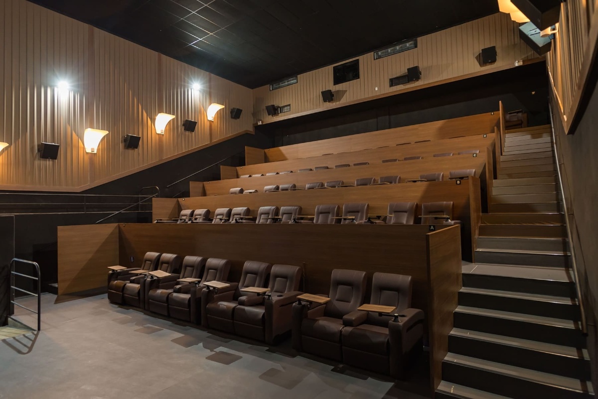 Sala de cinema com poltronas elétricas reclináveis e bandejas individuais